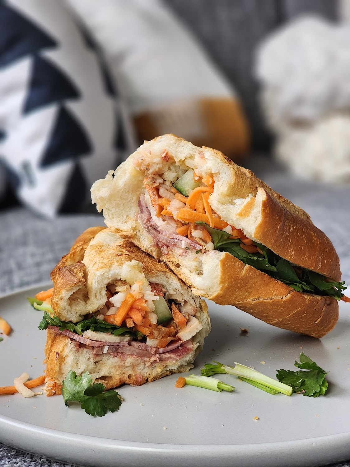 A banh mi sliced in half, fillings spilling out